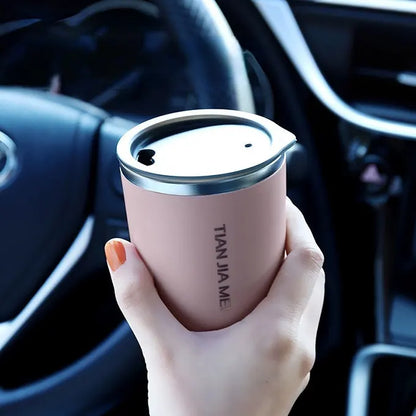 Main portant une tasse rose dans une voiture