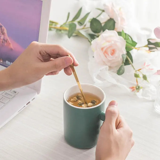 Personne qui mélange son thé dans une tasse sur son bureau de travail