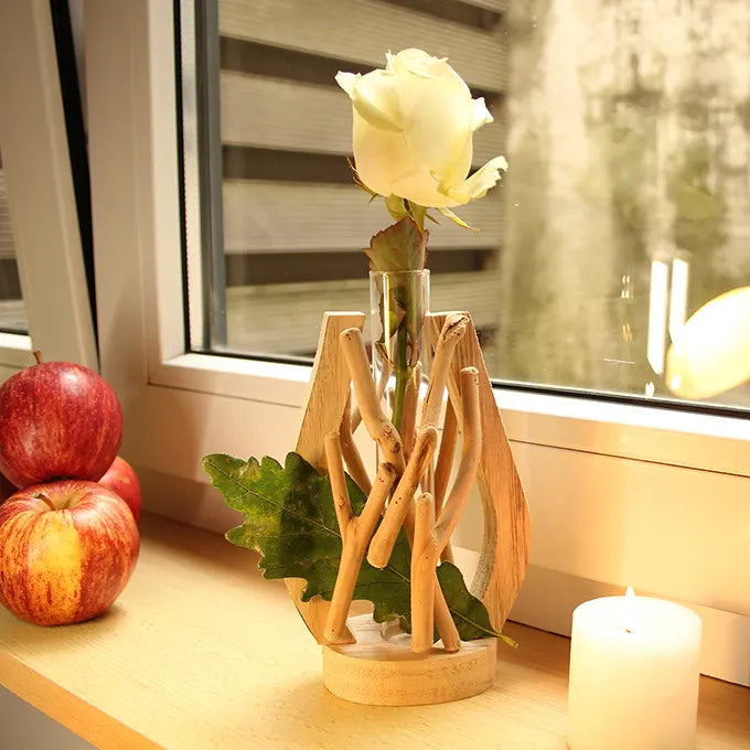 Vase tube au bord de la fenêtre avec une bougie, une rose blanche et des pommes