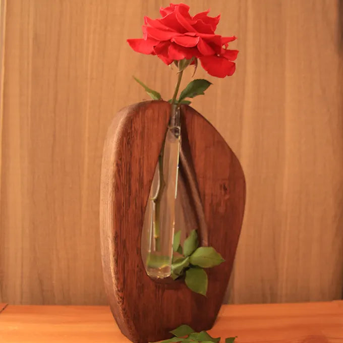 Vase tube en bois sur une table avec une fleur rose