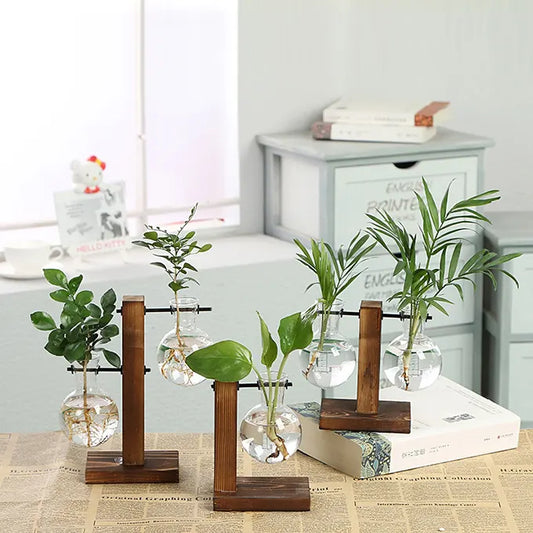 3 vases tubes présentés sur une table avec des plantes et décorations